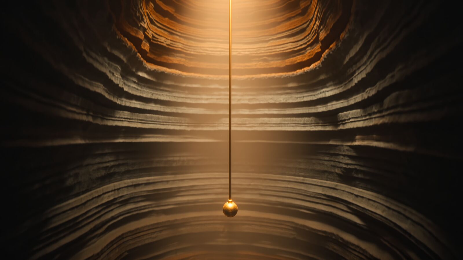 A brass plumb line hangs down the center of a stone shaft whose layered rock walls are lit from above.